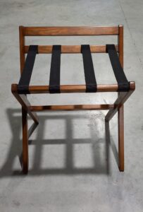 “Suporte de Malas para Hotéis em madeira, com quatro cintas resistentes, velatura média ou escura, barra de proteção de parede e estrutura dobrável para facilitar o uso da bagagem no quarto.”