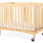 Berço de hotel dobrável em madeira clara modelo Travel Sleeper com rodas e colchão branco"